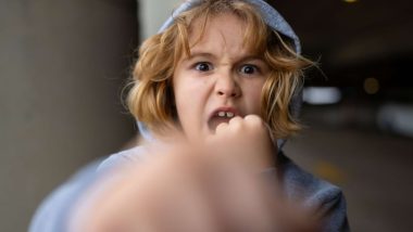 Copil cu expresie agresivă și pumnul ridicat spre cameră. Foto ilustrativ.