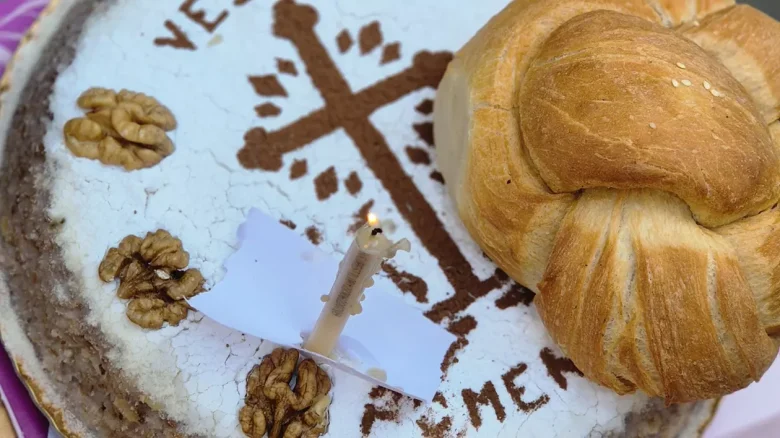 Colivă tradițională românească cu cruce din cacao, nuci și lumânare aprinsă, alături de colac, de Moșii de Vară. Foto ilustrativ.